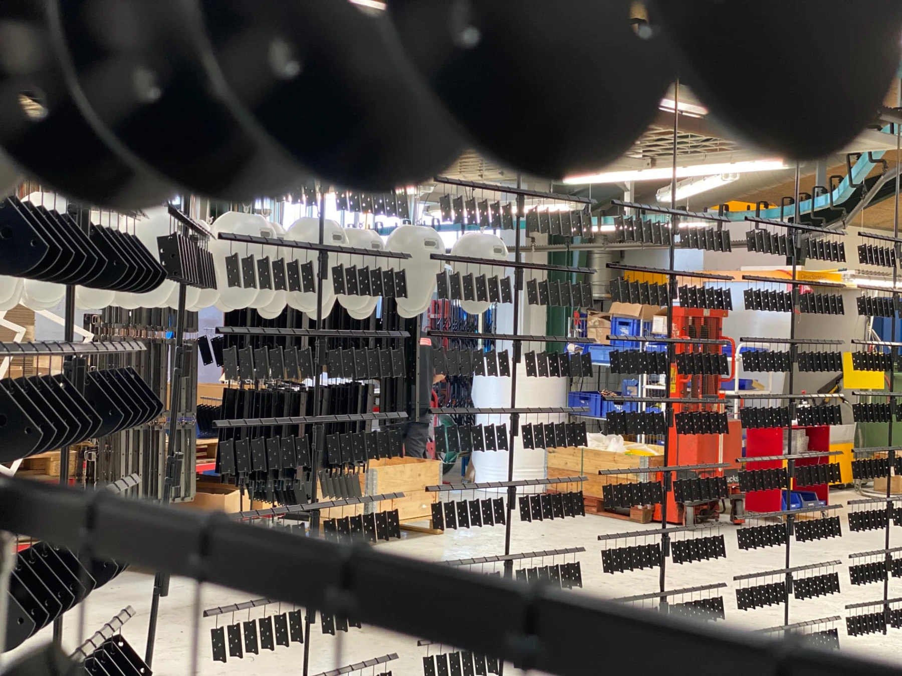 Små sorte emner ophængt til pulverlakering i produktionen hos 3N Lakering